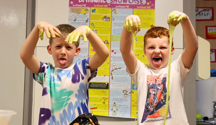 Two boys pulling silly faces whilst slime drips from their faces as they take part in the cognitive slime activity during an LSC Holiday Club