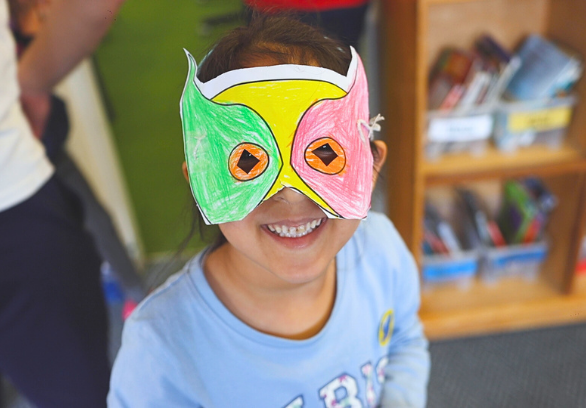 Child attending LSC multi-activity holiday club wearing self decorated mask from creative activity