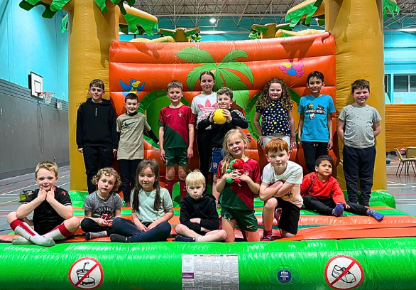 Children attending LSC Holiday Club sitting and standing on inflatable bouncy castle