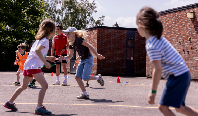 Group of primary school children running in a playground during LSC holiday club