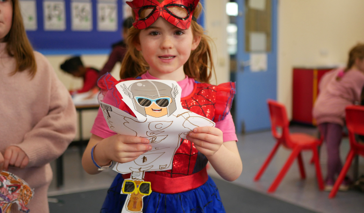 Child (girl) in fancy dress, wearing Spiderman outfit holding superhero she designed during LSC holiday club