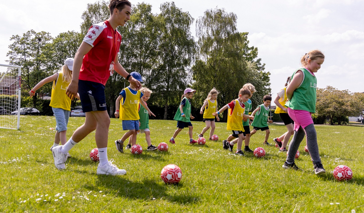 football holiday club- primary school aged children 4-11 kicking a football