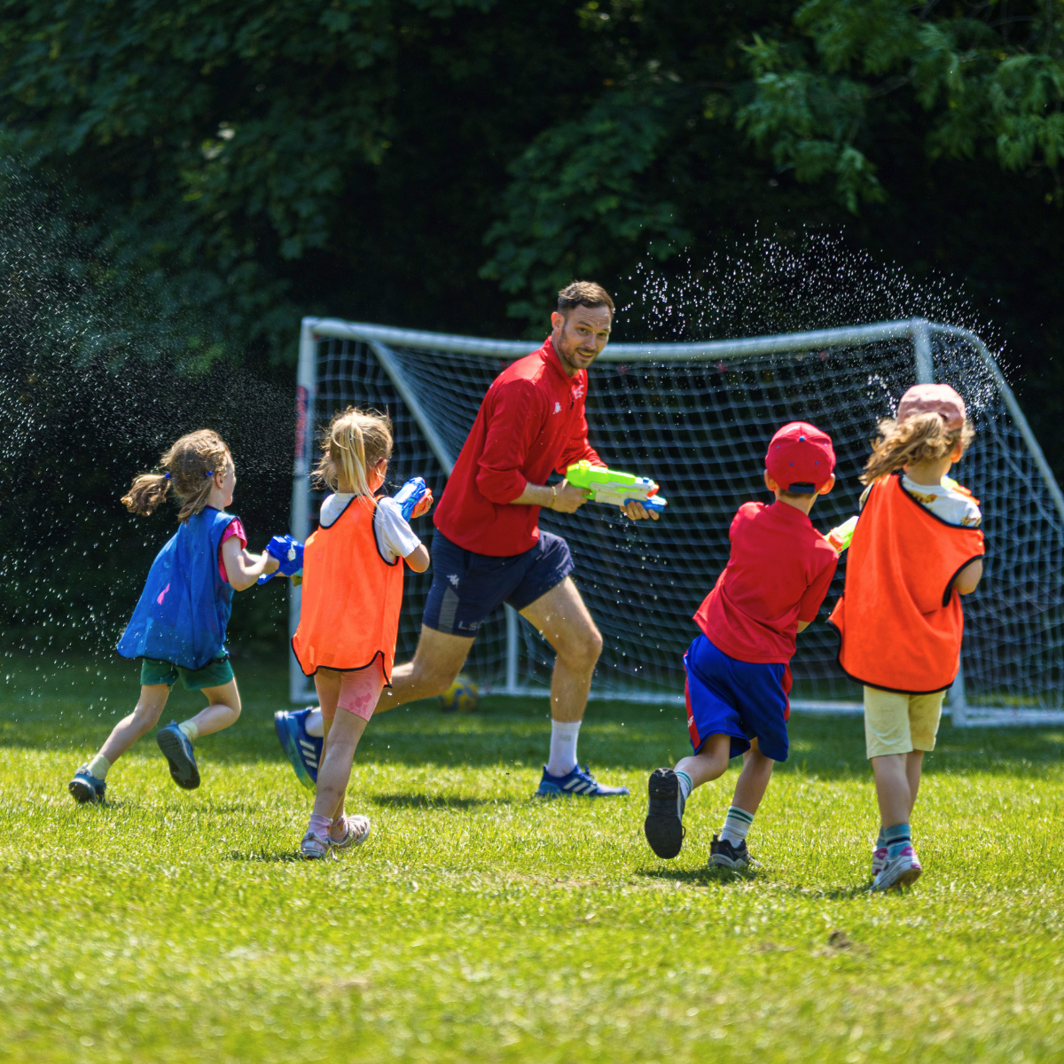 LSC Holiday Club practitioner wearing red top holding water pistol...