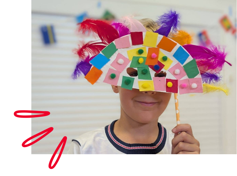 Child holding hand-made colourful mask to his face