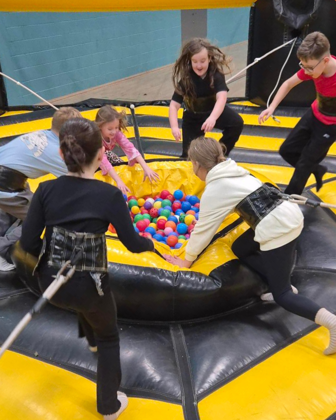Group of children participating in a grab challenge on a giant black and yellow inflatable